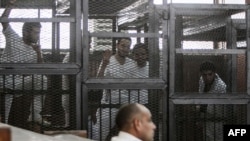 Defendants who are in custody stand in the accused cells during the trial of 20 individuals, including five Al-Jazeera journalists, for allegedly defaming the country and ties to the blacklisted Muslim Brotherhood on May 3, 2014.