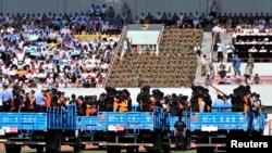 Trucks carrying criminals and suspects are seen during a mass sentencing rally at a stadium in Yili, Xinjiang, Uighur Autonomous Region, May 27, 2014.