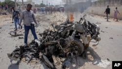 Pasukan keamanan dan warga sipil berkumpul di dekat reruntuhan setelah serangan bom mobil bunuh diri yang menargetkan pejabat tinggi Kepolisian di Mogadishu, Somalia, 10 Juli 2021. (Foto: AP)