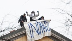 Reos de la cárcel de San Vittore, en Milán, se subieron al techo de la prisión para desplegar una pancarta solicitando un indulto ante la crisis sanitaria desatada por el coronavirus.