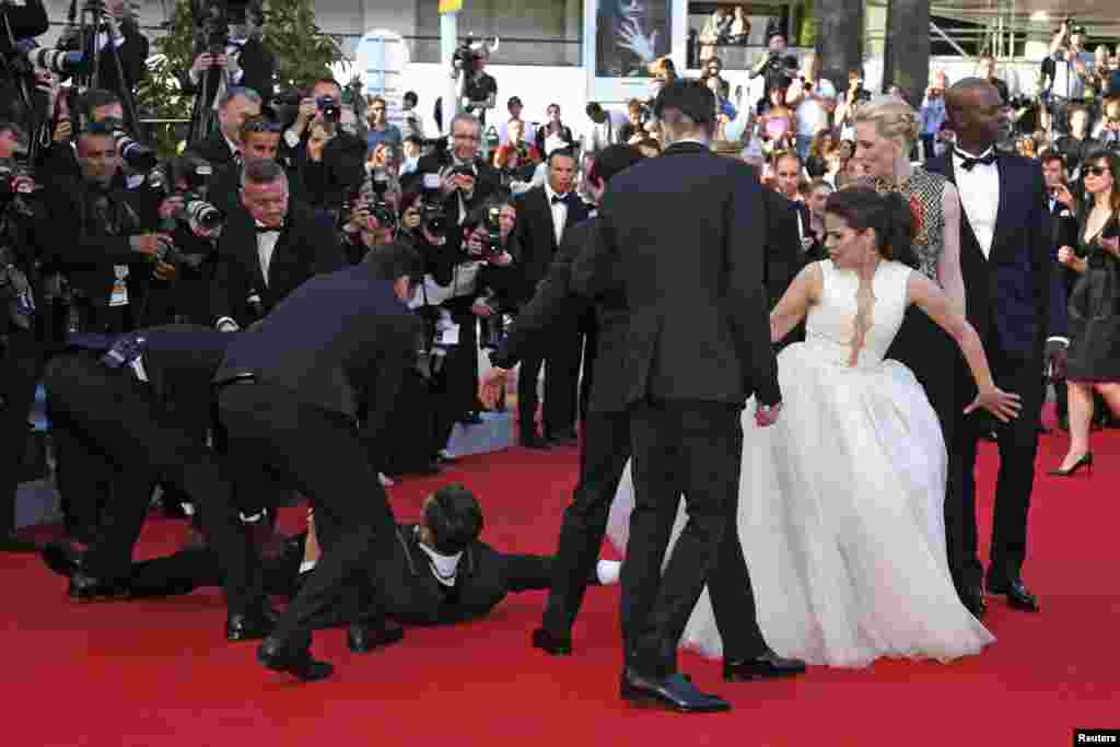 A man is arrested by security as he tries to slip under the dress of actress America Ferrera (3rd R) in Cannes, France, May 16, 2014.