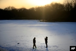 A couple takes photographs on a frozen pond at Franklin Delano Roosevelt Park in Philadelphia, Jan. 3, 2018.