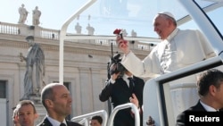 Pope Francis holds a flower thrown by a faithful as he arrives to lead a special audience with engaged couples, to celebrate Saint Valentine's day, in Saint Peter's Square at the Vatican, Feb. 14, 2014. 