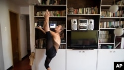 Carolina Wolf, integrante del Ballet Nacional de Venezuela, entrena en su sala mientras sigue un video de YouTube de Ernst Meisner del Ballet Nacional holandés, durante el confinamiento para frenar la propagación del COVID-19 en Caracas, Venezuela.