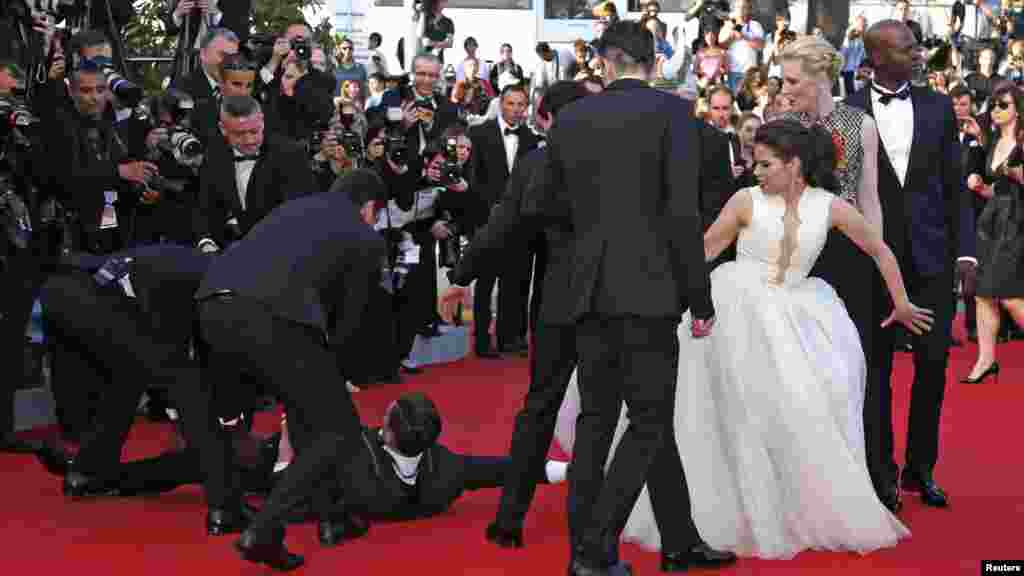 Un homme est arrêté par la sécurité alors qu'il tente de se glisser sous la robe de l'actrice America Ferrera (3 R) à Cannes, 16 mai 2014.