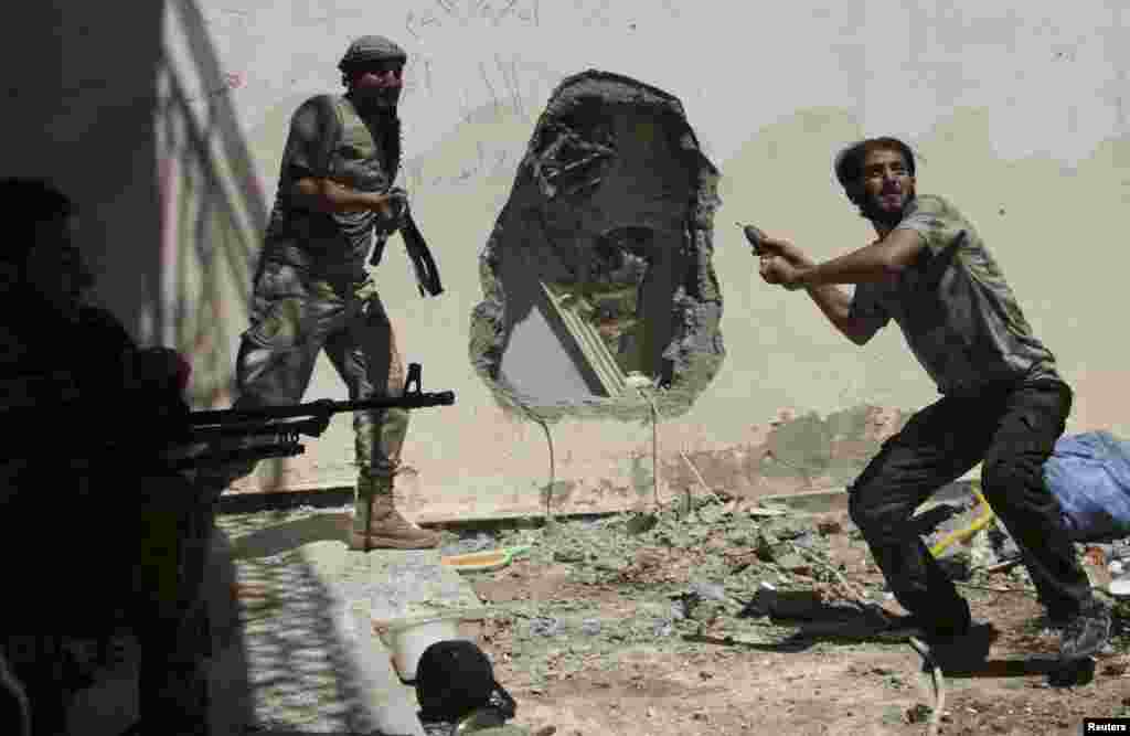 A Free Syrian Army fighter throws a homemade bomb towards forces loyal to Syria&#39;s President Bashar al-Assad as fellow fighters watch in Deir al-Zor, July 14, 2013.&nbsp;