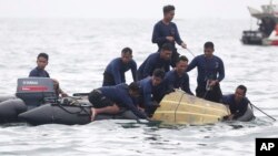 Para penyelam TNI Angkatan Laut menarik bagian dari puing pesawat Sriwijaya Air dari perairan di sekitar Kepulauan Seribu, Minggu (10/1). 