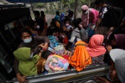 Warga duduk di atas mobil pick-up saat evakuasi pasca erupsi Gunung Semeru di Lumajang, Jawa Timur, 5 Desember 2021. (Foto: Antara/Umarul Faruq via REUTERS)