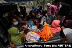Warga duduk di atas mobil pick-up saat evakuasi pasca erupsi Gunung Semeru di Lumajang, Jawa Timur, 5 Desember 2021. (Foto: Antara/Umarul Faruq via REUTERS)
