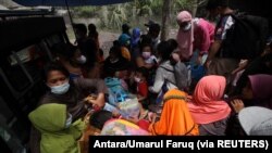 Warga duduk di atas mobil pick-up saat evakuasi pasca erupsi Gunung Semeru di Lumajang, Jawa Timur, 5 Desember 2021. (Foto: Antara/Umarul Faruq via Reuters)