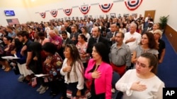 Calon warga negara AS membacakan Ikrar Kesetiaan selama upacara naturalisasi di kantor lapangan Layanan Kewarganegaraan dan Imigrasi AS Miami, Jumat, 16 Agustus 2019, di Miami. (Foto: AP)
