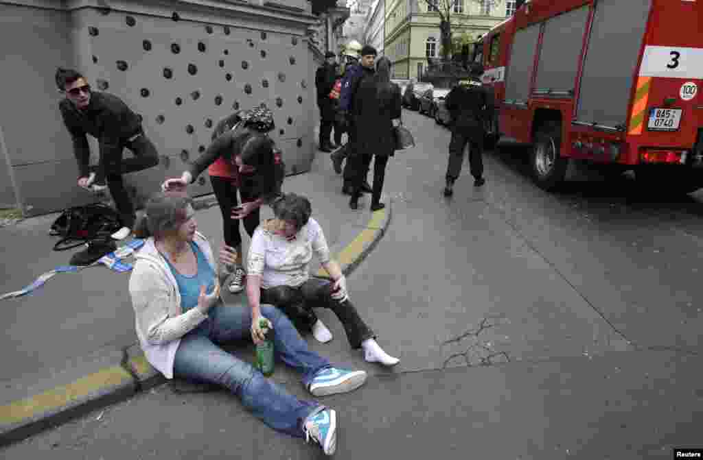 People sit on a sidewalk after an explosion in Prague, April 29, 2013. 