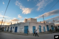 Boys walk past closed shops on the beginning of Shabbath, after sunset, at Hara Kbira, Djerba, southern Tunisia, Oct. 30, 2015.