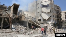 Ljudi ispred zgrade oštećene u najnovijem napadu na pobunjeničku četvrt Alepa