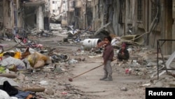 A child clears damage and debris in the besieged area of Homs, Syria, Jan. 26, 2014.