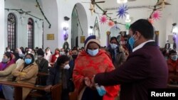 Seorang perempuan membersihkan tangannya sebelum menerima komuni di Gereja St Stephen saat perayaan Natal di kawasan lama Delhi, India, 25 Desember 2020. (Foto: REUTERS/Anushree Fadnavis)