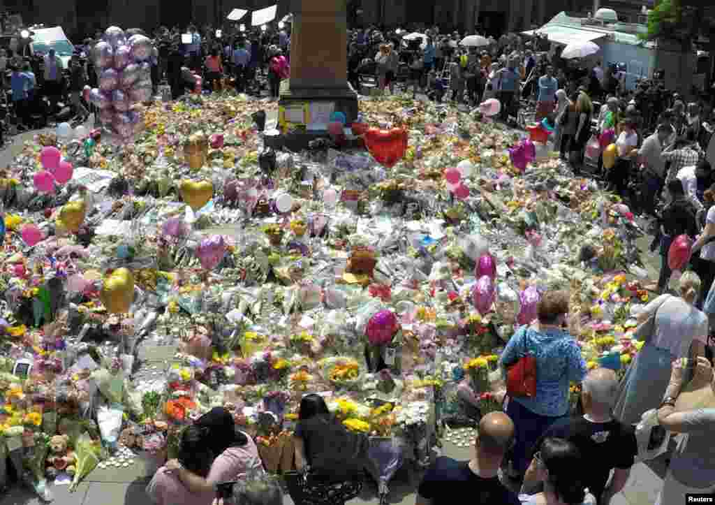 Crowds look at the balloons, flowers and messages of condolence left for the victims of the deadly Manchester Arena attack, in central Manchester, Britain.