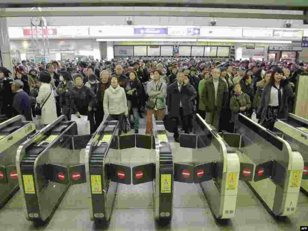 Люди, ожидающие прибытия поезда на станции метро «Кавасаки» в Токио. Движение поездов в токийском метро временно приостановлено в связи с цунами
