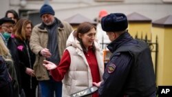 FILE— A police officer checks voters queuing at a polling station at noon local time in Moscow, Russia, on March 17, 2024. 