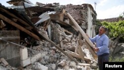 A man clears debris outside a damaged building after an earthquake stroked the area in Floq, Albania, June 1, 2019. 