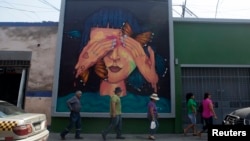 People walk next to a mural at Pachitea street in downtown Lima, March 12, 2015. 
