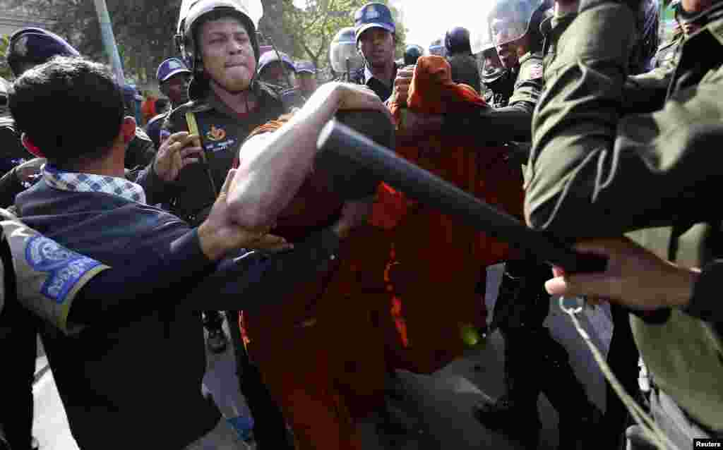 A Buddhist monk shields himself from police officers during a protest in front of the City Hall in central Phnom Penh, Cambodia. About 100 former Boeung Kak lake residents, including Buddhist monks, demanded that the government provide them with more compensation over their forced eviction from the area, to pave way for a private real estate development project, according to protesters.