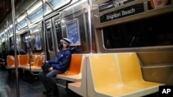 A commuter wears a face mask while riding the a nearly empty subway car into Brooklyn, in New York, March 12, 2020.