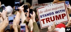 FILE - Supporters of Republican presidential candidate Donald Trump hold up phones and signs at a rally at Radford University in Radford, Virginia, Feb. 29, 2016.