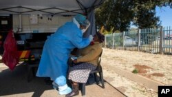 A woman has a sample collected for coronavirus testing during the screening and testing campaign aimed to combat the spread of COVID-19, in Eldorado Park outside of Johannesburg, South Africa, Aug. 3, 2020.