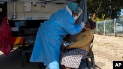 FILE: A woman has a sample collected for coronavirus testing during the screening and testing campaign aimed to combat the spread of COVID-19, in Eldorado Park outside of Johannesburg, South Africa, Aug. 3, 2020.