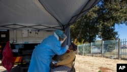 A woman has a sample collected for coronavirus testing during the screening and testing campaign aimed to combat the spread of COVID-19, in Eldorado Park outside of Johannesburg, South Africa, Aug. 3, 2020.