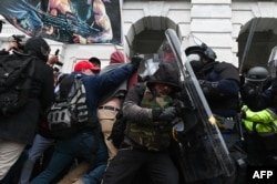 Polisi antihuru-hara memukul mundur kerumunan pendukung Presiden AS Donald Trump setelah mereka menyerbu Gedung Capitol AS pada 6 Januari 2021 di Washington, DC. (Foto: AFP)