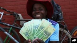 Un homme pose avec une liasse de nouveaux billets de banque de deux dollars introduits par la Banque de réserve du Zimbabwe à Harare, le 12 novembre 2019.