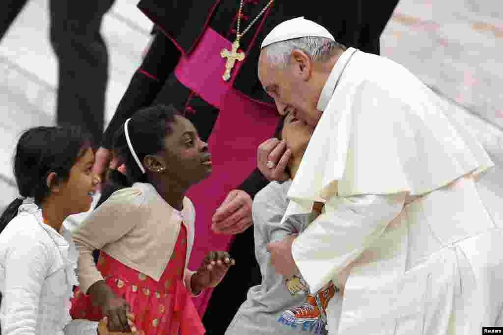 Paus Fransiskus menyapa anak-anak dalam sebuah pertemuan dengan komunitas setia Paus John XXIII di aula Paul VI di Vatikan, 20 Desember 2014.