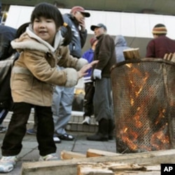 A girl warms herself at a shelter for quake-triggered tsunami survivors in Miyagi Prefecture.