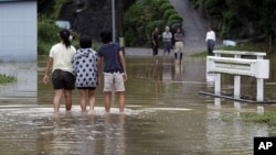 Local girls walk in a flooded street due to typhoon Roke in Toyota, central Japan September 21, 2011.