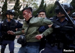 An unidentified injured man is escorted by riot police at Mong Kok in Hong Kong, China, Feb. 9, 2016.