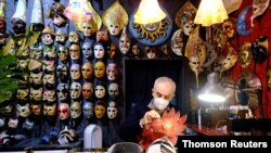 A mask artisan works inside his shop during what would have been Venice's annual colorful carnival, but was canceled this year due to the COVID-19 pandemic, in Venice, Italy, Feb. 7, 2021.