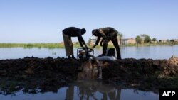 Two men start up a motor pump to clear floodwater in the Tougoude district in Chad, Oct. 8, 2024. Officials in Chad and Cameroon say flooding broke fiber-optic cables, causing a widespread internet outage. Others in Chad, however, say the government ordered the internet shutdown.