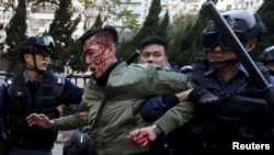 An unidentified injured man is escorted by riot police at Mongkok in Hong Kong, China February 9, 2016. 