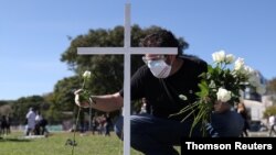 مردی در حال گذاشتن گل بر مزار یکی از اعضای کادر درمان که در اثر ابتلا به کووید۱۹ درگذشت