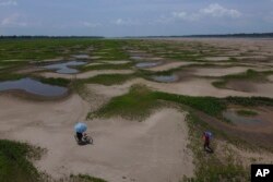 Para penduduk dari komunitas di tepi sungai membawa makanan dan wadah air minum setelah menerima bantuan di tengah kemarau panjang di Careiro da Varzea, negara bagian Amazonas, Brazil, Selasa, 24 Oktober 2023. (Foto: Edmar Barros/AP Photo)