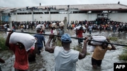 Les gens pillent des sacs de riz dans un entrepôt submergé par des eaux de crue du cyclone Idai, à Beira, Mozambique, le 20 mars, 2019.