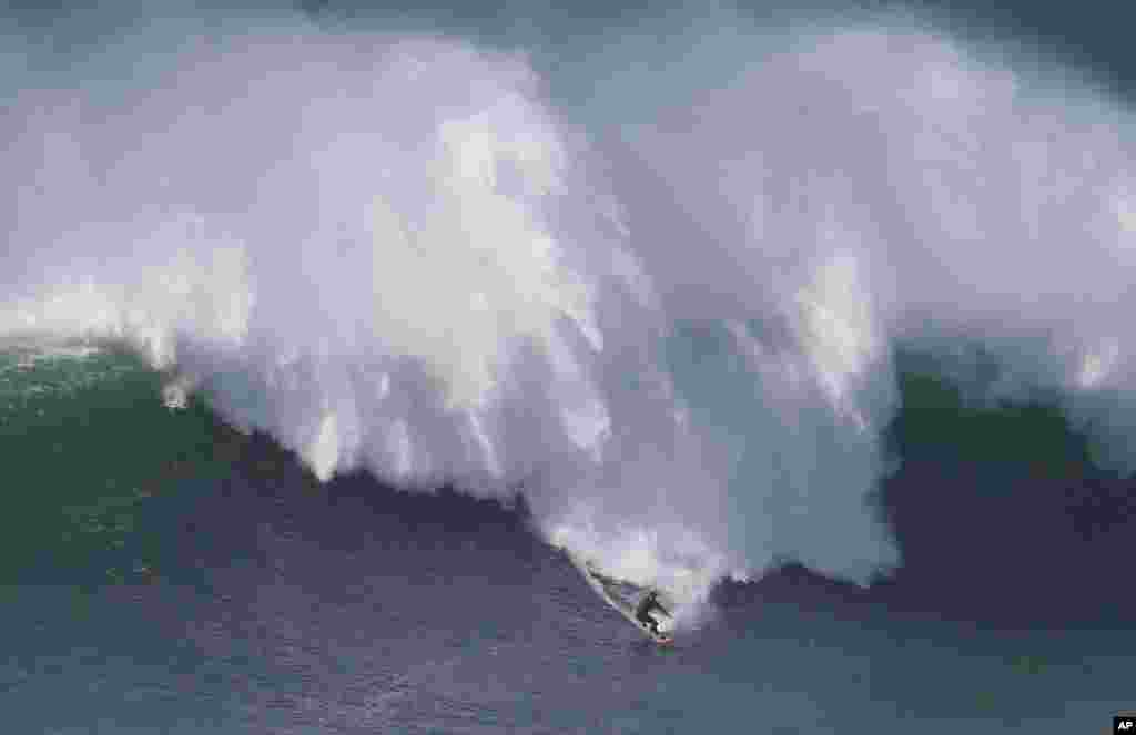 Rafael Tapia, from Chile, drops down a wave during a big wave surfing session at the Praia do Norte, or North beach, in Nazare, Portugal.