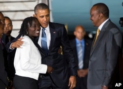 Kenyan President Uhuru Kenyatta, right, watches as President Barack Obama, center, hugs his half-sister Auma Obama, after he arrived at Kenyatta International Airport, on July 24, 2015, in Nairobi, Kenya.