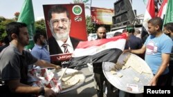 Palestinians carry trays of sweets and an Egyptian flag (C) in front of a placard depicting Egypt's Muslim Brotherhood's presidential candidate Mohamed Morsi in Gaza City, June 18, 2012.