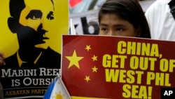 FILE - Protesters display a Philippine flag and placards while shouting slogans as they march towards the Chinese Consulate at the financial district of Makati city east of Manila.