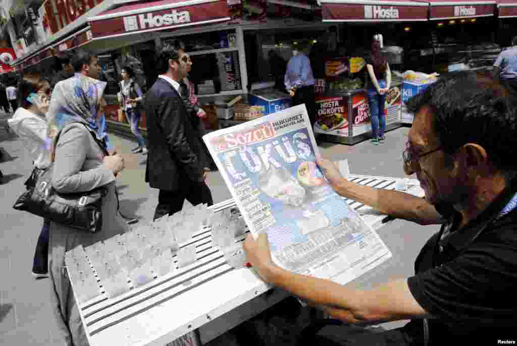 Um vendedor de bilhetes de lotaria lê um jornal turco publicado com a manchete, &quot;Queda&quot;, e um retrato do presidente Tayyip Erdogan da Turquia, em Ancara.