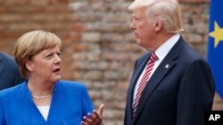 FILE - German Chancellor Angela Merkel, President Donald Trump, and other G-7 leaders (not seen) pose for a family photo at the Ancient Greek Theater of Taormina, May 26, 2017, in Taormina, Italy. 