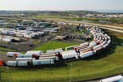 FILE - Trucks queue to embark aboard the freight shuttle at Eurotunnel terminal in Coquelles near Calais, France, Dec. 16, 2020.